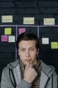 Thoughtful man pondering ideas in creative workspace with sticky notes behind.